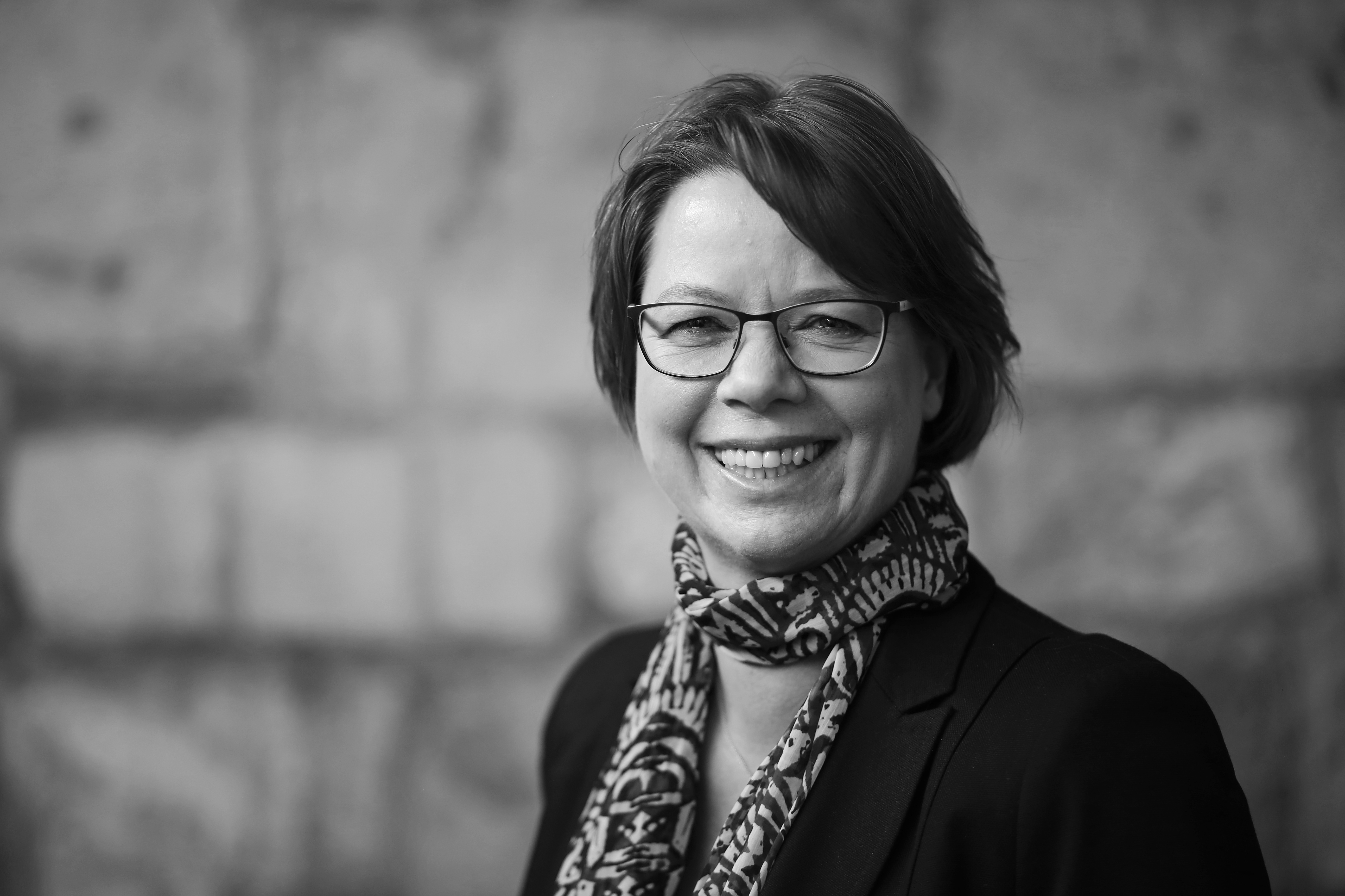 Iris Witt Schwarzweiß-Bild einer lächelnden Frau mit Kurzhaarfrisur und Brille, stellt Iris Witt dar