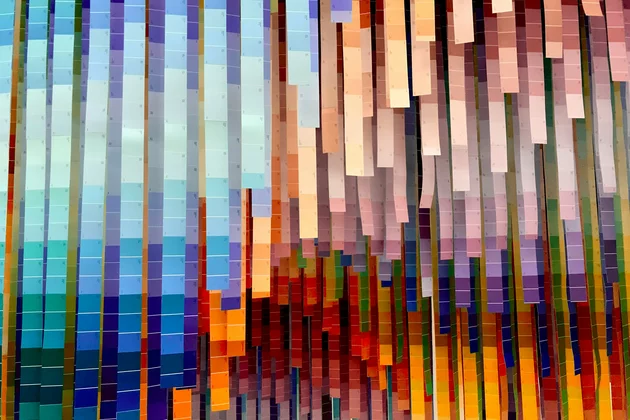 Das Bild zeigt bunte Farbproben in Papierform, die vond er Decke hängen. 