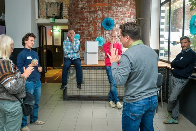 Das Bild zeigt eine Gruppe, die in einem Kreis steht und diskutiert.