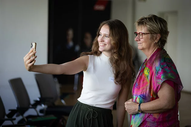 Das Bild zeigt zwei Personen, die mit dem Handy ein Selfiefoto aufnehmen.