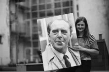 Das Bild zeigt eine junge Frau, die ein Portraitfoto von Heinrich Böll in die Höhe hält.