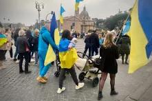 Menschen mit ukrainischen Flaggen (gelb-blau), die über die Straße laufen. 