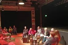 Die Teilnehmenden der Diskussion sitzen im Halbkreis vor den Zuschauenden. 