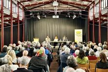 Im Hintergrund sind die Vortragenden zu sehen und im Fordergrund die Teilnehmenden