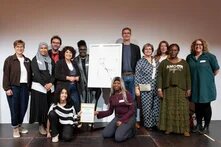 Gruppe von Menschen, die das Preisbild und die Preisurkunde hochhhalten und in in die Kamera schauen. 
