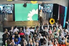 Das Bild zeigt eine Menschenmenge, die in einem Saal sitzt.