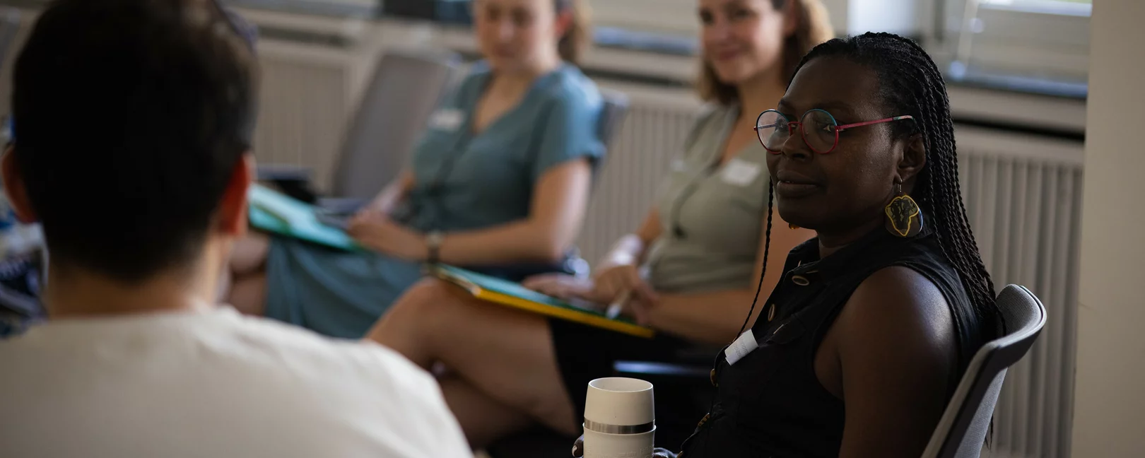 Das Bild zeigt mehrere Personen im Stuhlkreis, die einander zuhören.