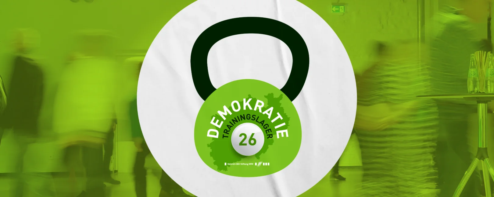Eine grüne Kettlebell mit der Aufschrift Demokratie-Trainingslager 2026, dahinter ein verschwommenes Bild von Menschen, die sich durch einen Raum bewegen.