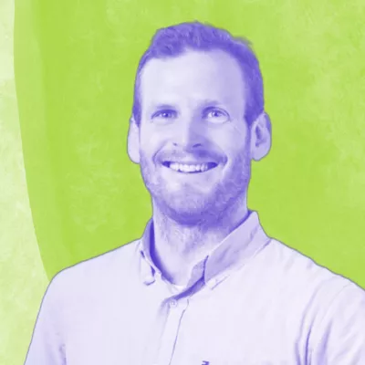 Porträt von Niklas Henke. Er lächelt in die Kamera, das Bild ist blau eingefärbt auf grünem Hintergrund.