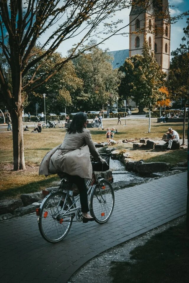 Frau in grauer Jacke auf einem Fahrrad durch den Stadtpark Bielefeld
