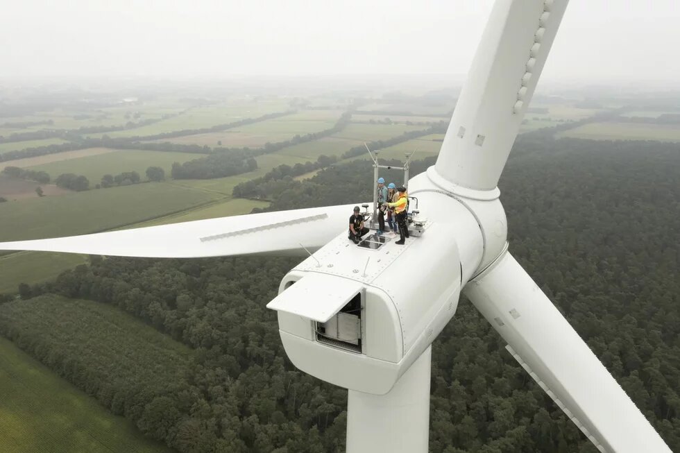 DAs Bild zeigt eine Gruppe von Menschen auf einem Windrad, von oben fotografiert.
